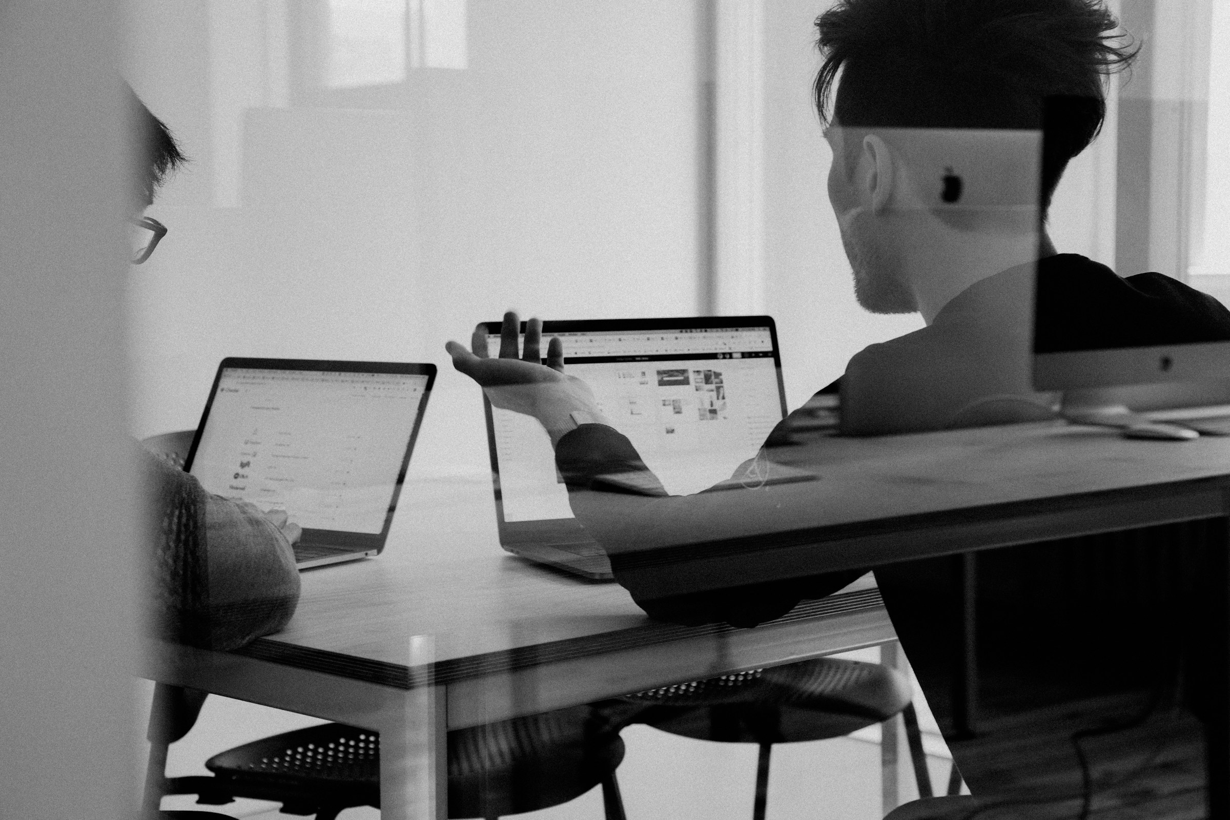 Partners in conversation over laptops during a working meeting